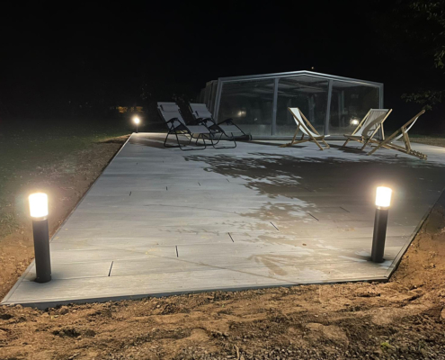 Photo de nuit de la terrasse aménagée à côté de la piscine