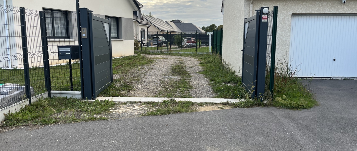 Photo de l'aménagement extérieur d'un client avant création de son parking à Bourg-Achard en Seine-Maritime. Vue du côté portail